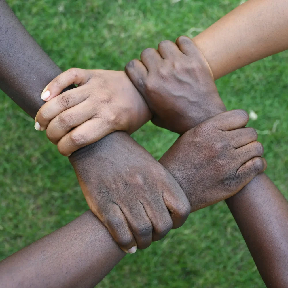 Multiple hands interlinked in a circular formation, representing solidarity and collective strength among participants.